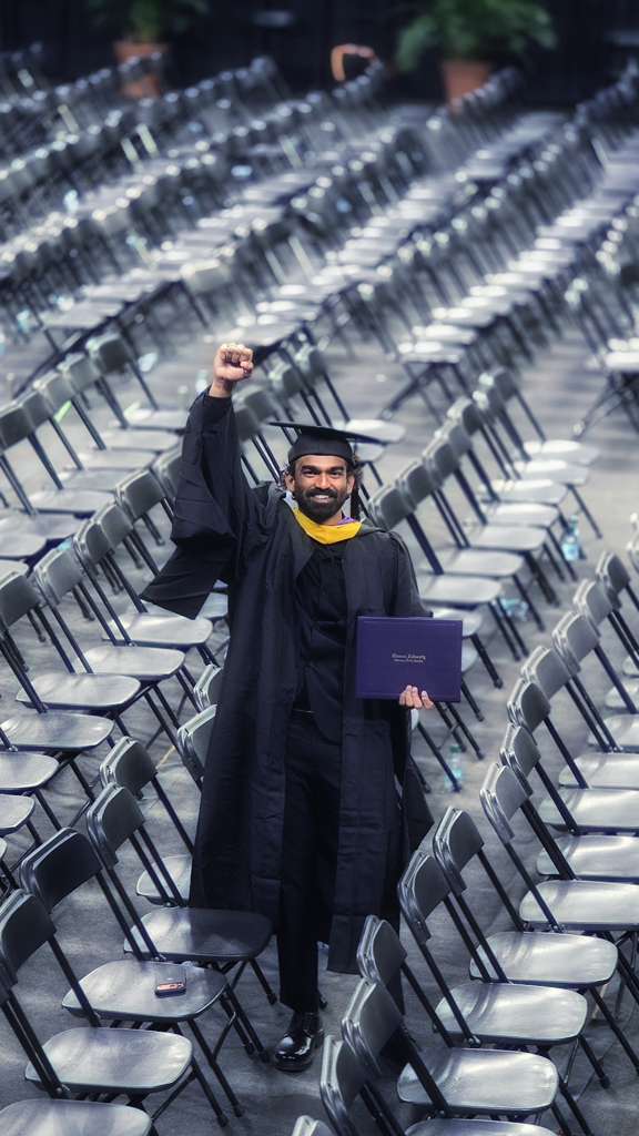 Ajay Chowdary Dodda in cap and gown at graduation, raising a fist in celebration